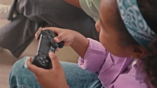 Fentről lövés vidám afro-amerikai gen z lány és a modern anya segítségével vezérlők, miközben játszik a játékkonzol otthon - Felvétel, videó