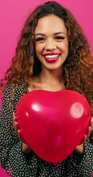 Krásná mladá žena drží srdce ve tvaru balónu směrem ke kameře, studio. Vysoce kvalitní 4K záběry - Záběry, video