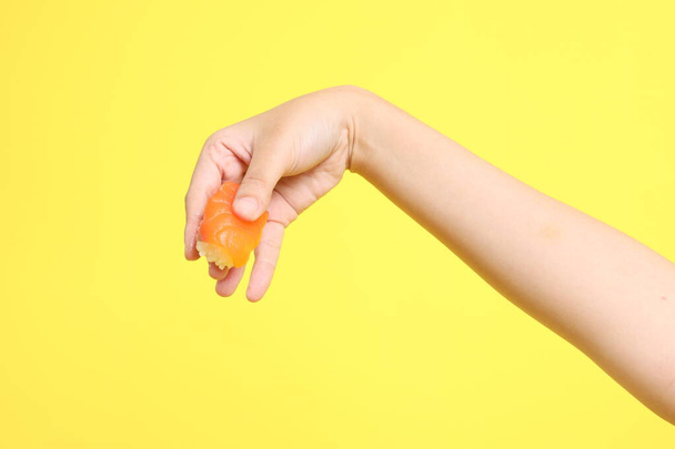 Asijka ruka drží sushi v purpurovém pozadí. - Fotografie, Obrázek