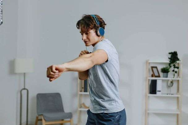 чоловік внутрішній поверх людина кімната спорт оздоровчі технології онлайн активність відсутність домашнього способу життя навушники тренування здоров'я тренування здоровий сірий спортивний одяг - Фото, зображення