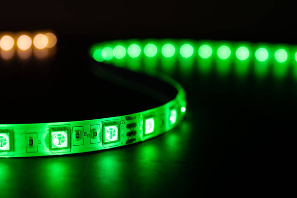Masanın üzerine yeşil ve ılık beyaz renkte parıldayan LED şerit ışıklandırmalı bobbin. - Fotoğraf, Görsel