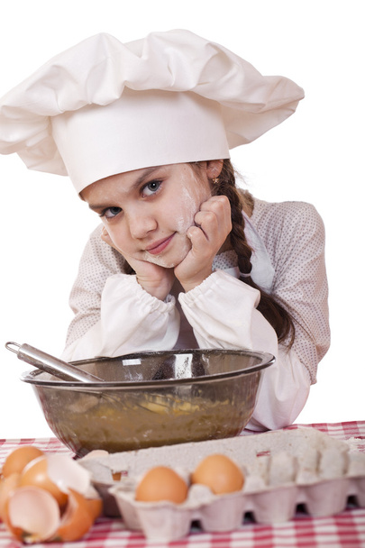 Little girl in a white apron breaks near the plate with eggs - Фото, изображение