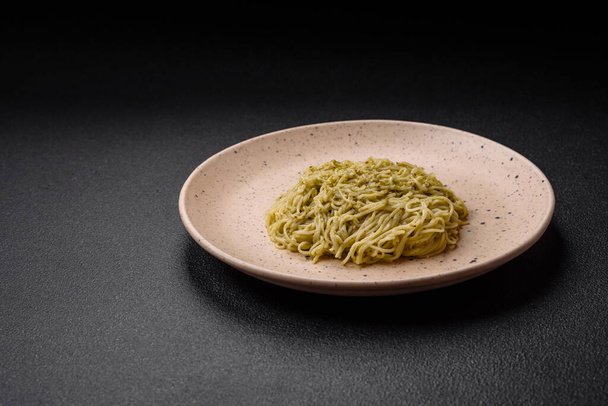 Capellini pasta of noedels met pestosaus, zout en specerijen op een donkere betonnen ondergrond - Foto, afbeelding