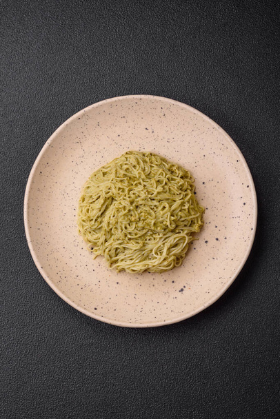 Ζυμαρικά Capellini ή noodles με σάλτσα πέστο, αλάτι και μπαχαρικά σε σκούρο μπετόν φόντο - Φωτογραφία, εικόνα