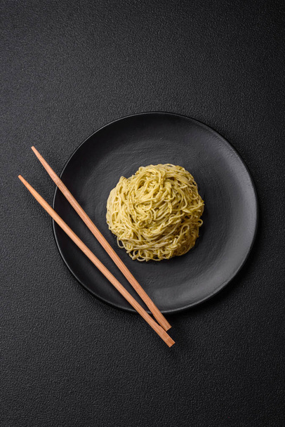 Ζυμαρικά Capellini ή noodles με σάλτσα πέστο, αλάτι και μπαχαρικά σε σκούρο μπετόν φόντο - Φωτογραφία, εικόνα