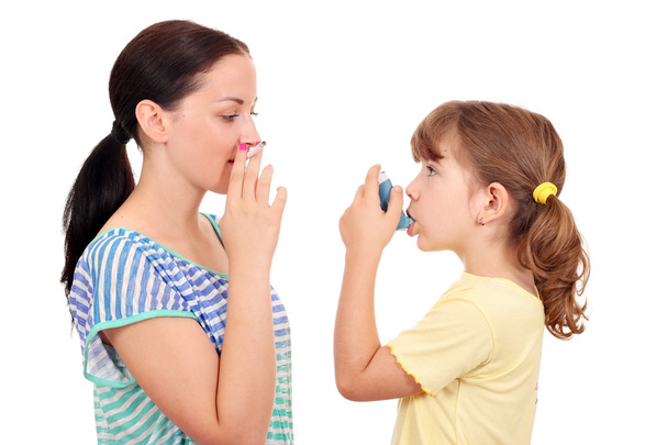 girl smoking cigarette and little girl with inhaler - Foto, afbeelding