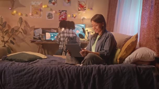 Nowoczesna Biracial matka siedzi na łóżku w pokoju córki mając wideo czat na laptopie późno w nocy - Materiał filmowy, wideo