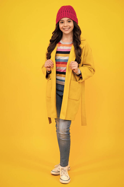 Full length of pretty cheerful teenager girl having fun good mood and posing in casual autumn coat isolated over yellow background. Happy teenager, positive and smiling emotions of teen girl - Photo, Image