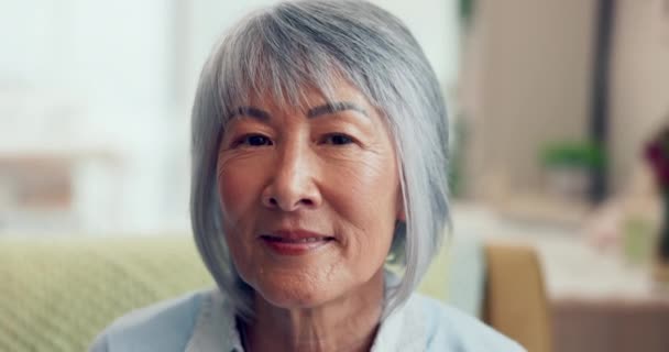 Cara, jubilación y feliz con una mujer asiática de último año en la sala de estar de su casa de cerca. Retrato, arrugas y canas con una pensionista anciana sentada en su casa para relajarse sola. - Imágenes, Vídeo