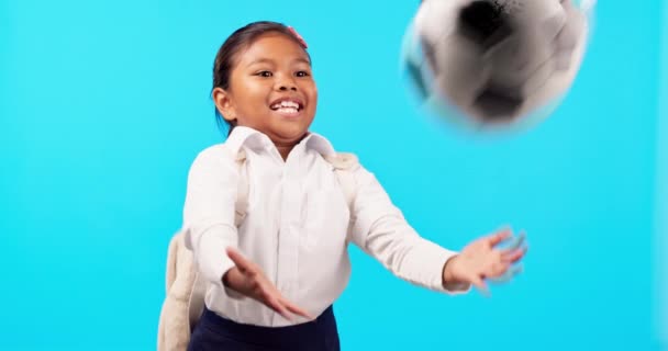 Παιδιά, μπάλα και μπάλα ποδοσφαίρου με μια μαθήτρια σε μπλε φόντο στο στούντιο για παιχνιδιάρικη διασκέδαση. Παιδιά, χαμόγελο και ένα χαρούμενο νεαρό θηλυκό παιδί με ένα ποδόσφαιρο έτοιμο να απολαύσει ένα παιχνίδι των σπορ. - Πλάνα, βίντεο