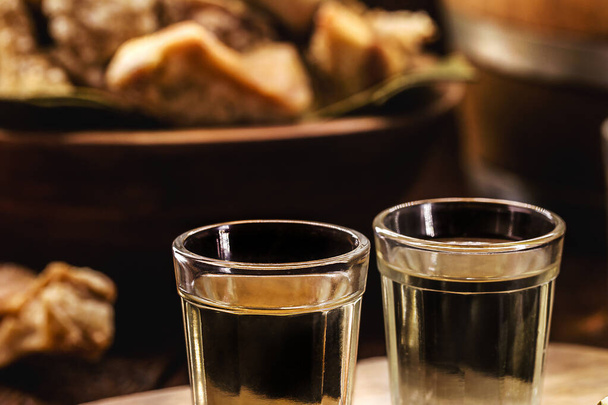 Cachaca, pinga, cana o caninha es el brandy de caña de azúcar, una bebida típica de Brasil, con un aperitivo crujiente en el fondo - Foto, imagen