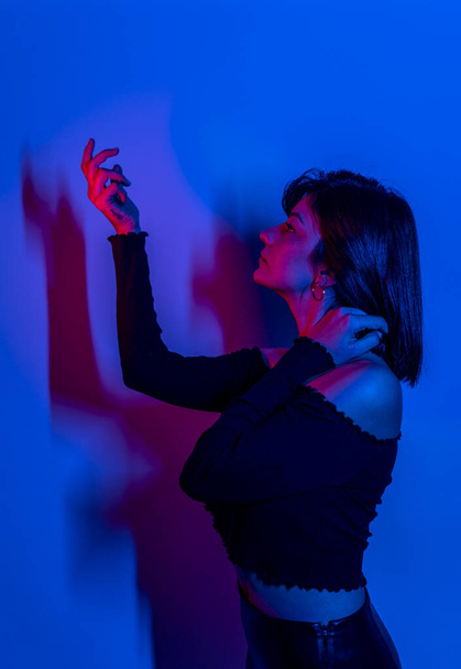 Vysoká Módní modelka žena v barevných jasných neonově modrých a fialových světlech pózující ve studiu. Portrét krásné ženy s módní zářící make-up. Design umění živý styl - Fotografie, Obrázek