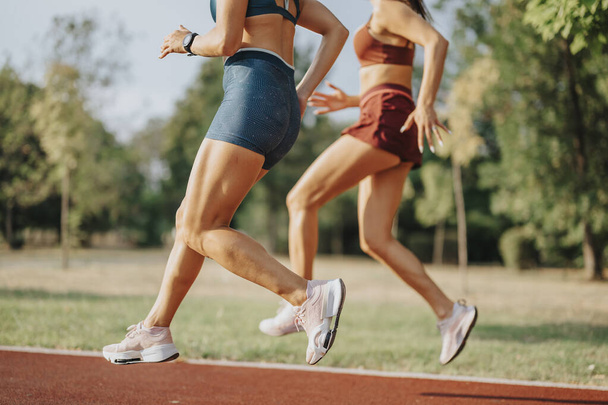 Подходящие девушки, бегущие на природе: спортивные женщины, выполняющие упражнения на свежем воздухе для здорового образа жизни и тренировок - Фото, изображение