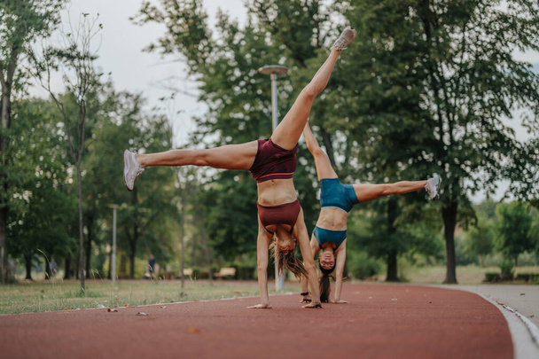 Девушки вдохновляют своими спортивными телами, выполняя 360-градусные перевороты и колеса на открытом воздухе. Подтянутые девушки демонстрируют гибкость и силу, демонстрируя свою мотивацию к здоровому образу жизни. - Фото, изображение
