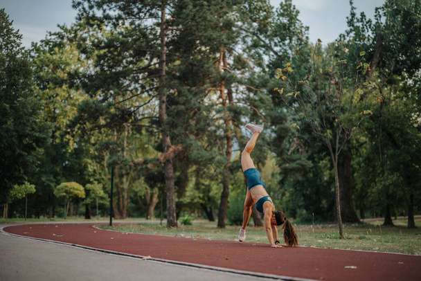 Fit girl demonstrating strength, flexibility, and athleticism during an inspiring outdoor workout. Motivating others to stay active and embrace a healthy lifestyle. - Photo, Image