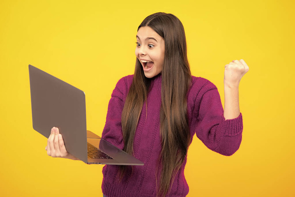 Возбужденное лицо. Молодая студентка держит компьютер. Смешной ученик с ноутбуком изолированный фон. Возвращайся в школу. Удивительное выражение лица, жизнерадостное и радостное. - Фото, изображение