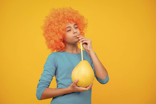 Yaz meyveleri. Genç bir kız çocuğu sarı arka planda izole edilmiş narenciye meyve suyu ya da pomelo tutar. Çocuk sağlıklı besleniyor - Fotoğraf, Görsel