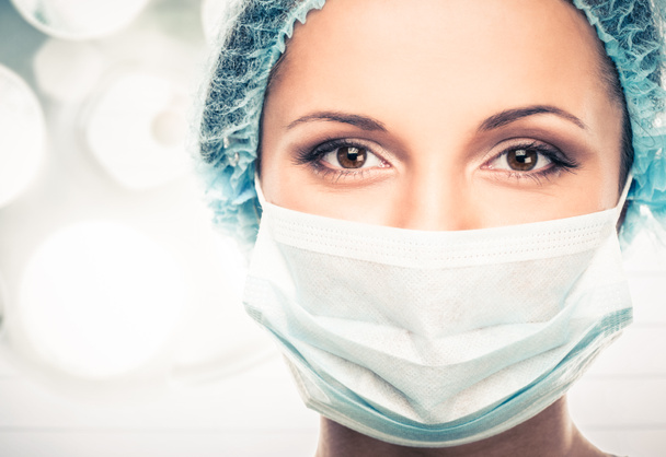 Mujer joven doctora en gorra y mascarilla en quirófano interior
 - Foto, imagen