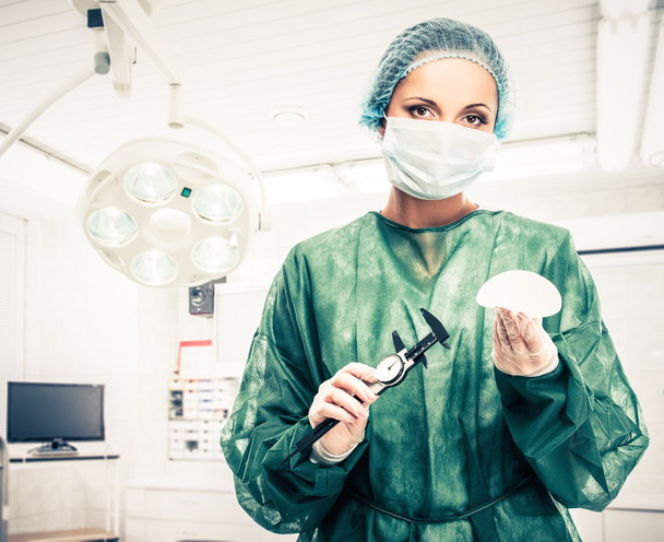 Πλαστικός χειρουργός γυναίκα με εμφύτευμα στήθους από σιλικόνη και παχύμετρο στο χειρουργείο  - Φωτογραφία, εικόνα