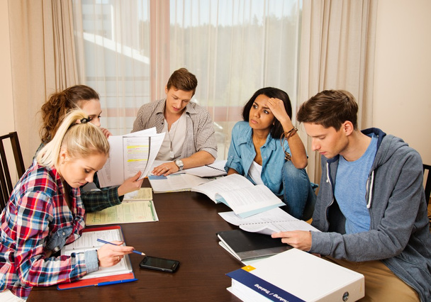 Multi ethnic group of students preparing for exams in home interior behind table  - Photo, Image