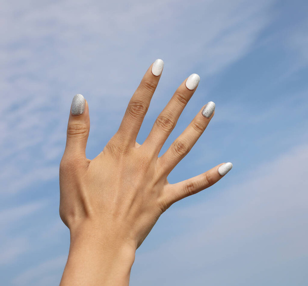 ręka młodej dziewczyny z pięciu paznokci z kolorowym lakierem do paznokci i błękitne niebo - Zdjęcie, obraz