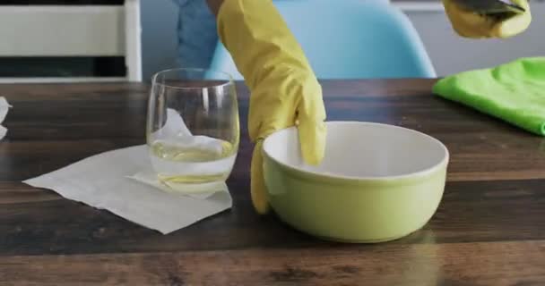 Ama de casa en guantes de goma limpia mesa de madera en la cocina. Las hembras limpian la cocina después de la cena y preparan vajilla sucia para lavar - Metraje, vídeo