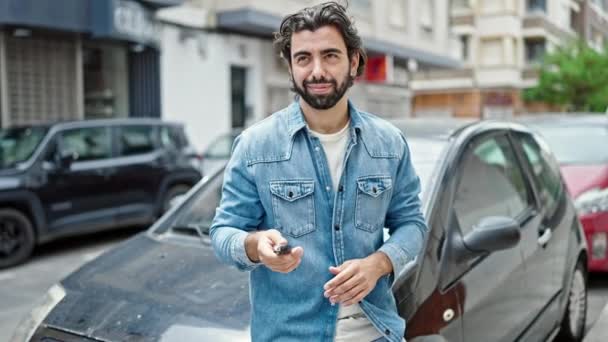 Young hispanic man smiling confident holding key of new car at street - Filmagem, Vídeo