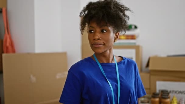 Femme afro-américaine bénévole souriant confiance debout au centre de charité - Séquence, vidéo