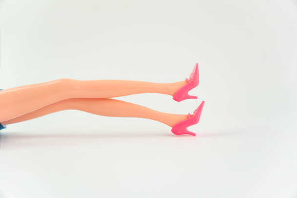 Muñeca piernas sobre fondo blanco, piernas delgadas, espacio para copiar. - Foto, Imagen