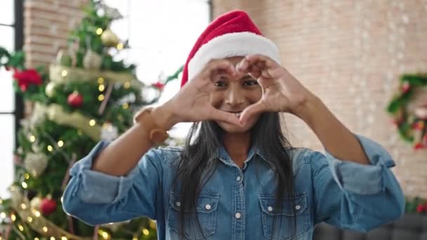 Afrykańska amerykanka świętuje Boże Narodzenie robiąc kształt serca rękami w domu - Materiał filmowy, wideo