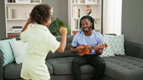 Afroamerikanisch Vater und Tochter spielen Ukulele tanzen zu Hause - Filmmaterial, Video