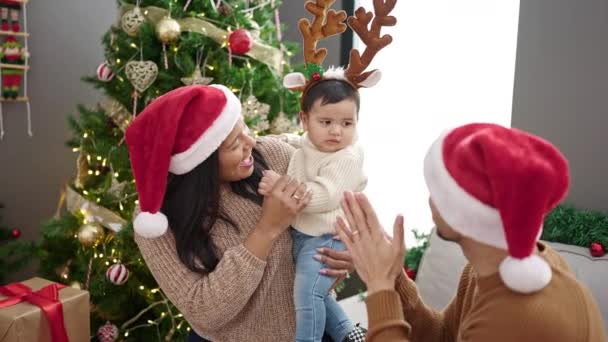 Paar en zoon dragen rendieren oren zittend op de bank door kerstboom thuis - Video