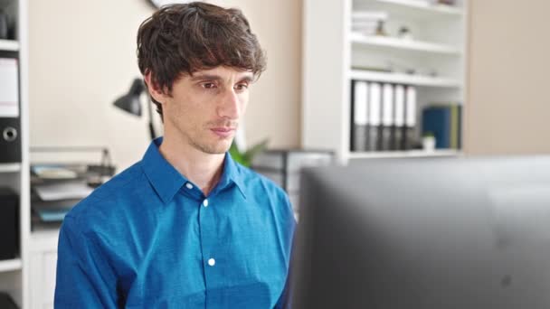 Nuori latino mies liiketoiminnan työntekijä käyttää tietokonetta ja älypuhelinta toimistossa - Materiaali, video