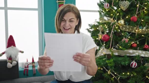 Middle age hispanic woman reading christmas letter at home - Footage, Video