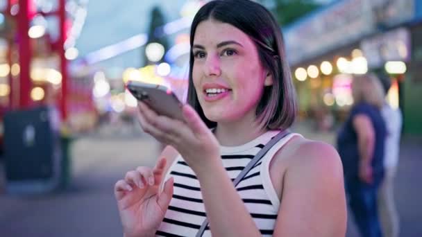 Junge schöne hispanische Frau sendet Sprachnachricht mit Smartphone im Wiener Prater - Filmmaterial, Video