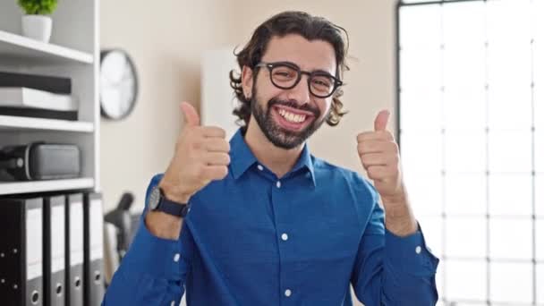 Молодий іспаномовний чоловік бізнесмен робить великі пальці вгору жест в офісі - Кадри, відео