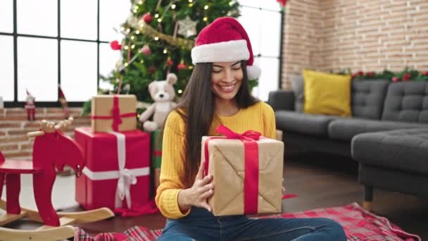 Νεαρή όμορφη ισπανόφωνη γυναίκα γιορτάζει τα Χριστούγεννα κρατώντας δώρο στο σπίτι - Πλάνα, βίντεο