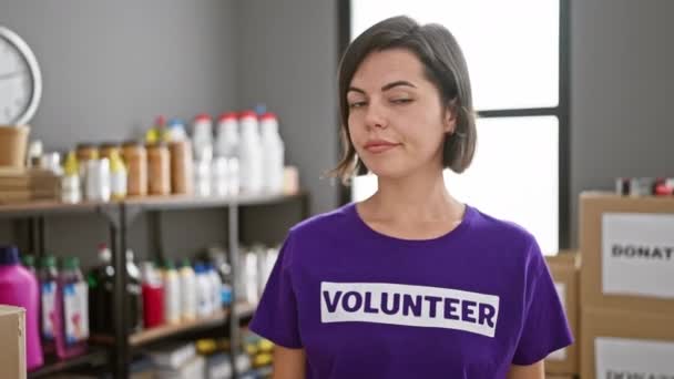 Serieus gezicht, jonge Spaanse vrouw, mooi gekleed in uniform, vrijwilligerswerk in een liefdadigheidscentrum, geconcentreerd op het uitpakken van donatiedozen - Video
