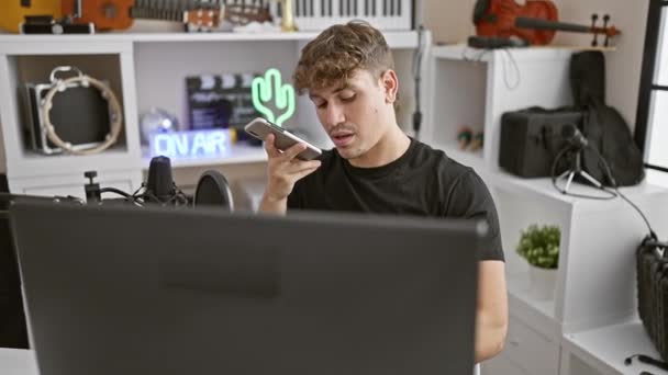 Молодой латиноамериканец-музыкант отправляет голосовое сообщение на смартфон в студию радио - Кадры, видео