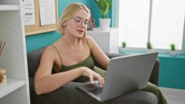 Nuori blondi nainen liiketoiminnan työntekijä etsii katsella sulkeminen kannettava tietokone rentouttava toimistossa - Materiaali, video