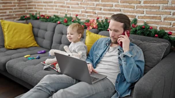 Otec a syn slaví Vánoce hraní s hračkami pomocí notebooku doma - Záběry, video