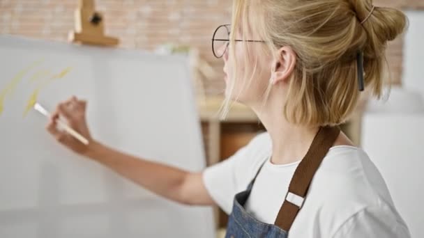 Jonge blonde vrouw kunstenaar tekening geconcentreerd in kunststudio - Video