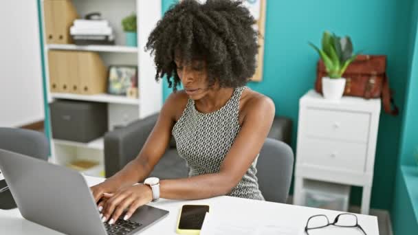 Afrikkalainen amerikkalainen nainen liike-elämän työntekijä käyttää laptop yllään lasit lukea asiakirjaa toimistossa - Materiaali, video