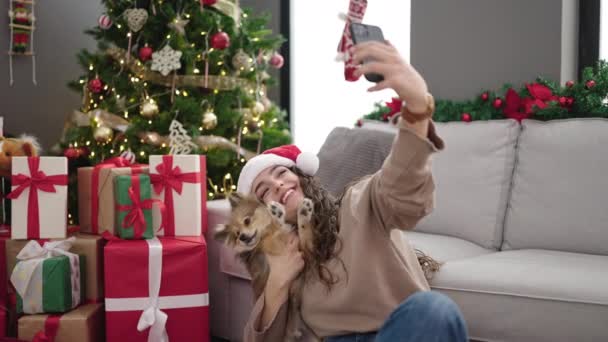 犬を持つ若いヒスパニックの女性は自宅でクリスマスを祝うスマートフォンでセルフィーを作ります - 映像、動画