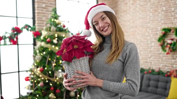 Νεαρή λευκή γυναίκα που κρατάει χριστουγεννιάτικο φυτό στο σπίτι - Πλάνα, βίντεο