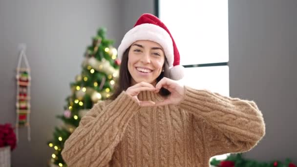 Fiatal gyönyörű spanyol nő ünnepli karácsony csinál szív alakja a kezét az utcán - Felvétel, videó