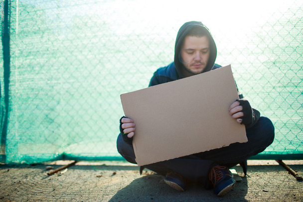 Homeless man holds blank cardboard for your text - Valokuva, kuva