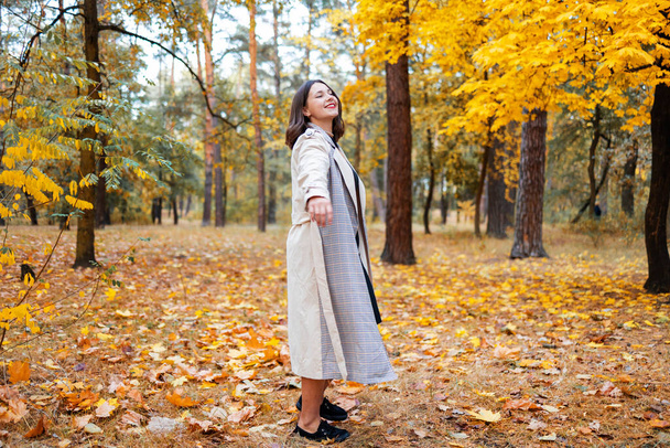 Χαριτωμένη χαμογελαστή γυναίκα κρατώντας φύλλα του φθινοπώρου στη φύση. - Φωτογραφία, εικόνα