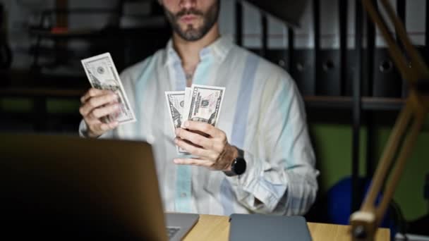 Молодий іспаномовний чоловік бізнесмен рахує долари в офісі - Кадри, відео