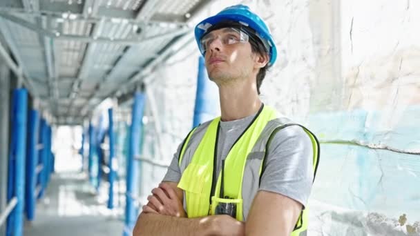Mladý hispánský muž architekt stojící se zkříženýma rukama a vážnou tváří na staveništi - Záběry, video